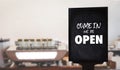 Come in WeÃ¢â¬â¢re OpenÃ¢â¬â¢ on cafe waiter standing in front of coffee shop vintage Royalty Free Stock Photo